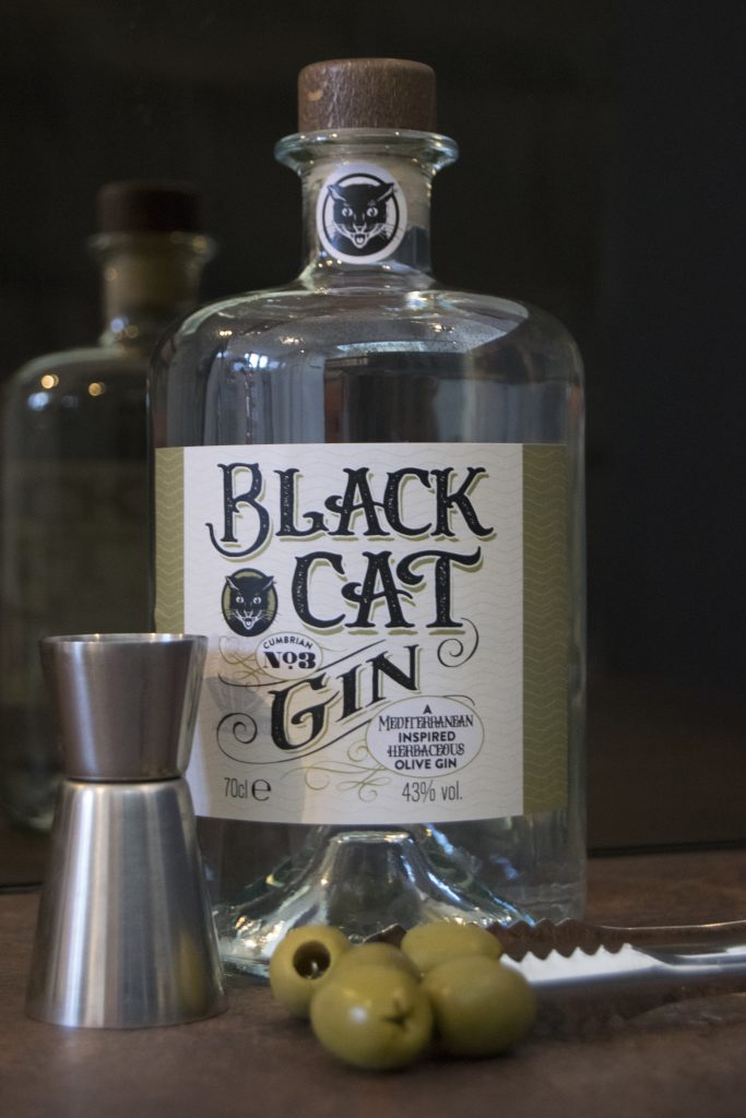 Bottle of Black Cat Savoury gin Cumbrian No 3 with jigger, tongs and olives in the foreground